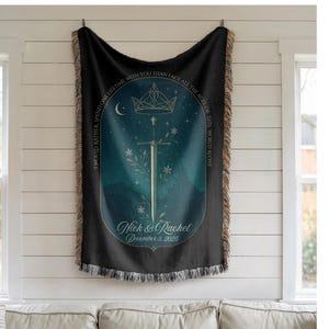 Op de afbeelding: Zwarte geweven sprei met een decoratief ontwerp met een zwaard, kroon en bloemmotieven. De deken heeft een blauwgroen en marine kleurenschema met de tekst "Ik zou liever een leven met jou doorbrengen dan alle tijden van deze wereld alleen onder ogen te zien." De namen "Nick & Rachel" en de datum "3 december 2025" zijn ook opgenomen.