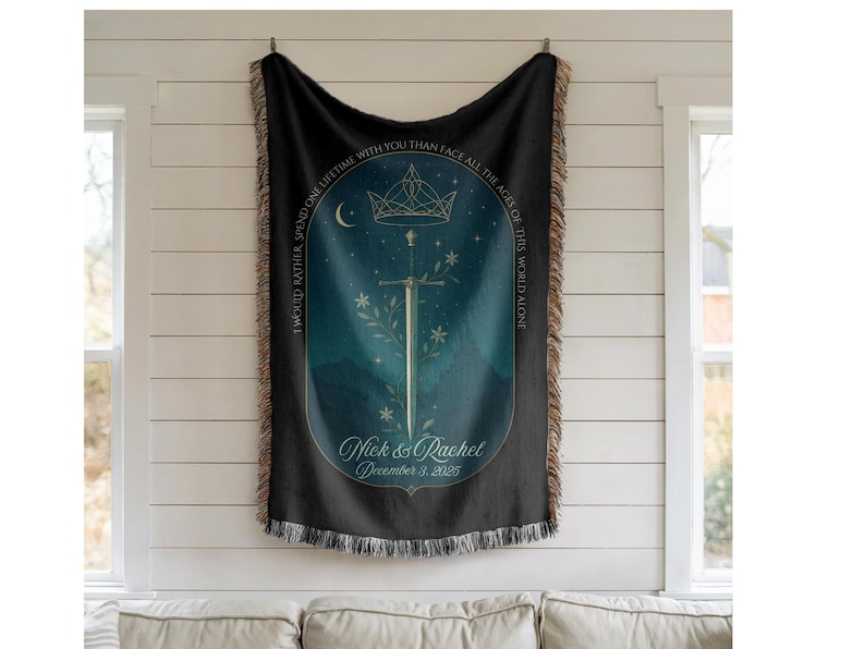 Op de afbeelding: Zwarte geweven sprei met een decoratief ontwerp met een zwaard, kroon en bloemmotieven. De deken heeft een blauwgroen en marine kleurenschema met de tekst "Ik zou liever een leven met jou doorbrengen dan alle tijden van deze wereld alleen onder ogen te zien." De namen "Nick & Rachel" en de datum "3 december 2025" zijn ook opgenomen.