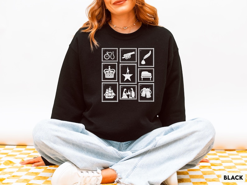 Puede incluir: Sudadera negra con nueve ilustraciones de sellos postales blancos. Los sellos representan una bicicleta, un ca&ntilde;&oacute;n, una pluma, una corona, una estrella, un piano, un barco, figuras y jarras de cerveza. La palabra "BLACK" est&aacute; impresa en la parte inferior derecha.