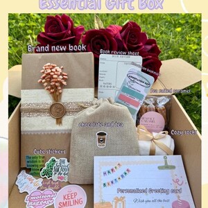 May include: An open gift box filled with a brand new book, a book review sheet, annotation bookmarks, sea salted caramel, cozy socks, chocolate and tea, cute stickers, and a personalized birthday greeting card. The box is decorated with red roses.