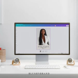 May include: A computer monitor displays a design featuring a woman in a white blazer. The text "AURA STUDIO molly jane" is visible. A white keyboard, mouse, and speakers are on the desk. The text "BLUSHNBRAND" is at the bottom.