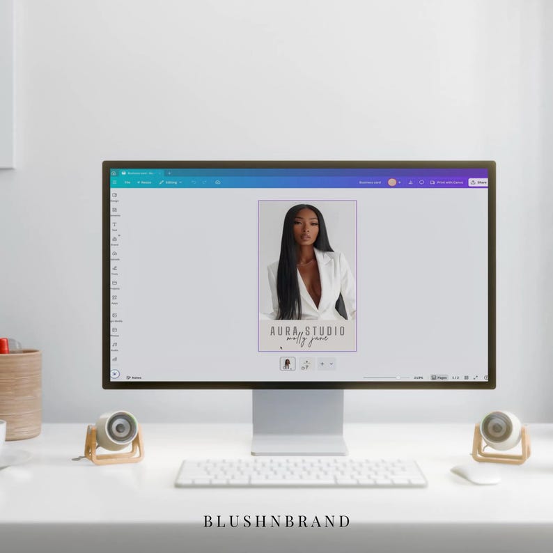 May include: A computer monitor displays a design featuring a woman in a white blazer. The text "AURA STUDIO molly jane" is visible. A white keyboard, mouse, and speakers are on the desk. The text "BLUSHNBRAND" is at the bottom.