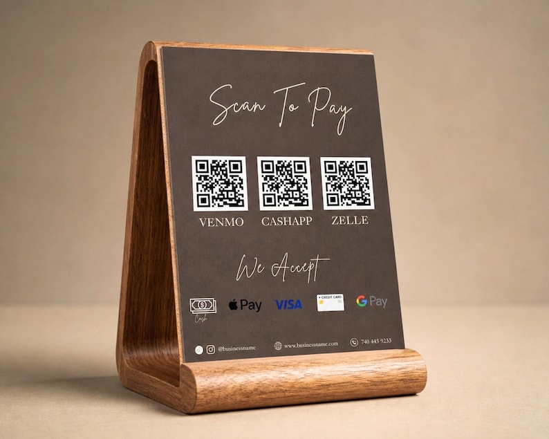 A warm lifestyle product shot showing the dark brown luxury price list template displayed upright in a wooden tabletop stand with a large scan to pay QR code panel and We Accept text visible representing how the luxury price list looks as a physical desk display giving hair salon owner, wig seller, and beauty professional a premium in person payment and service menu solution