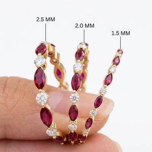 Op de afbeelding: Drie gouden ringen met afwisselend marquise-geslepen rode edelstenen en ronde witte stenen. De ringen zijn gelabeld met breedtes van 2,5 MM, 2,0 MM en 1,5 MM, wat de grootte aangeeft van de rode edelstenen die in de gouden banden zijn gezet.