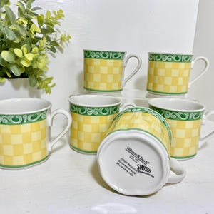 May include: Set of six Villeroy & Boch Switch mugs. Each mug features a yellow and white checkered pattern with a green decorative border. The mugs have white handles and are suitable for microwave and dishwasher use.