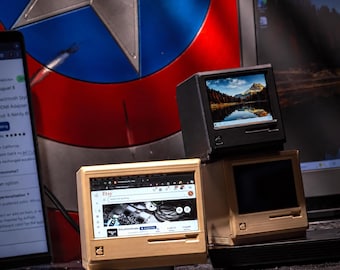 May include: Three miniature computer monitors designed in a vintage style. One black unit displays a landscape image, while two beige units feature a small Apple logo and a screen showing an Etsy webpage. The devices are compact and desktop-sized.