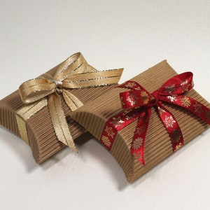 May include: Two small, brown cardboard gift boxes with decorative ribbon bows. One box has a gold ribbon bow and the other has a red ribbon bow with gold snowflake accents.