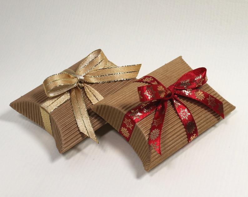 May include: Two small, brown cardboard gift boxes with decorative ribbon bows. One box has a gold ribbon bow and the other has a red ribbon bow with gold snowflake accents.