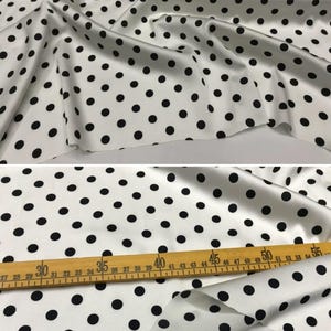 Peut inclure: Tissu blanc &agrave; pois noirs. Le tissu est drap&eacute;, r&eacute;v&eacute;lant sa texture et son mouvement. Le texte "0.8cm" est visible. Une r&egrave;gle en bois indique des mesures en centim&egrave;tres.