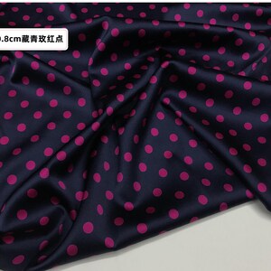 Peut inclure: Tissu bleu marine fonc&eacute; avec un motif de pois rose vif. Le tissu est pli&eacute;, montrant la texture et le lustre du mat&eacute;riau. Le texte sur l'image indique "0,8 cm de points bleu fonc&eacute; et rouges."