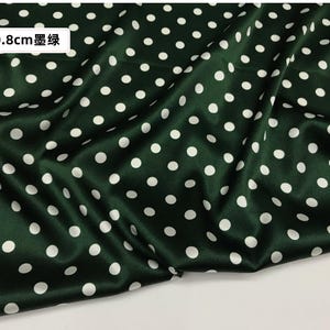 Peut inclure: Tissu vert fonc&eacute; &agrave; pois blancs. Le tissu a un aspect satin&eacute; et est drap&eacute;, montrant la texture et le flux du mat&eacute;riau. Le texte sur l'image indique "0,8 cm 墨绿".