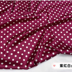 Peut inclure: Tissu bordeaux &agrave; pois blancs. Le tissu est drap&eacute;, cr&eacute;ant des plis et des ombres. Les pois sont espac&eacute;s uniform&eacute;ment et de taille constante, ajoutant un &eacute;l&eacute;ment ludique au design. Le tissu a un l&eacute;ger &eacute;clat.