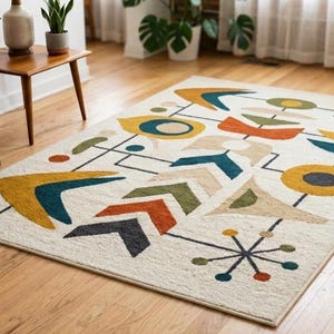 May include: A rectangular area rug with a mid-century modern design. The rug features a cream background with geometric shapes in yellow, teal, orange, and black. The rug is placed on a hardwood floor.
