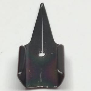 Puede incluir: Una plumilla de metal negro para pluma caligr&aacute;fica, con punta afilada y un peque&ntilde;o orificio circular. La plumilla tiene un acabado oscuro e iridiscente, dise&ntilde;ada para escritura y dibujo detallados.