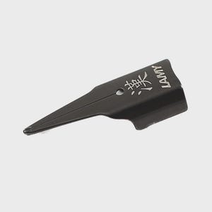 Puede incluir: Una plumilla negra con la palabra "LAMY" y caracteres japoneses grabados en plata. La plumilla tiene una punta afilada y una base plana. La plumilla est&aacute; dise&ntilde;ada para caligraf&iacute;a y escritura.