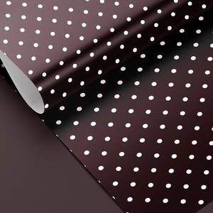 May include: A roll of brown wrapping paper with a white polka dot pattern. The paper is partially unrolled, revealing a solid brown underside. The polka dots are evenly spaced across the surface.