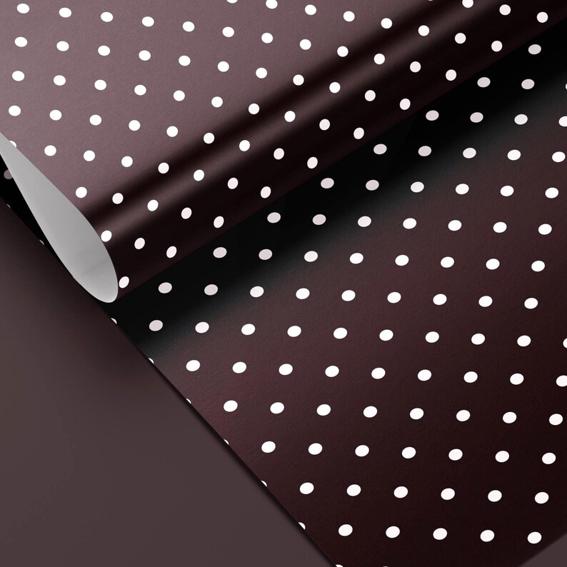 May include: A roll of brown wrapping paper with a white polka dot pattern. The paper is partially unrolled, revealing a solid brown underside. The polka dots are evenly spaced across the surface.