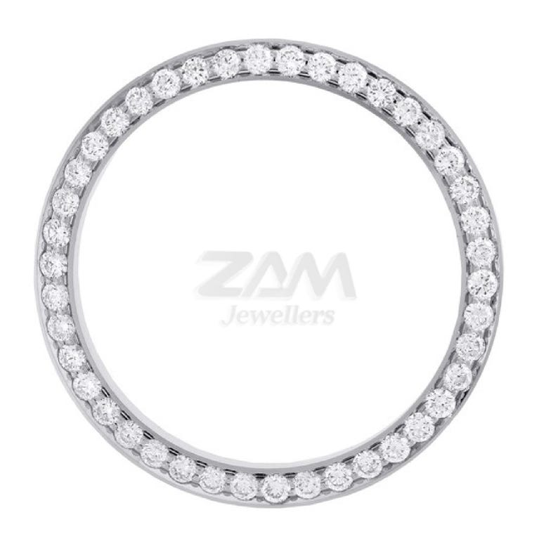 K&ouml;nnte beinhalten: Eine silberfarbene L&uuml;nette mit einem Ring aus kleinen, runden, klaren Edelsteinen. Die Edelsteine sind gleichm&auml;&szlig;ig um die L&uuml;nette angeordnet. Der Text "ZAM Jewellers" befindet sich in der Mitte.