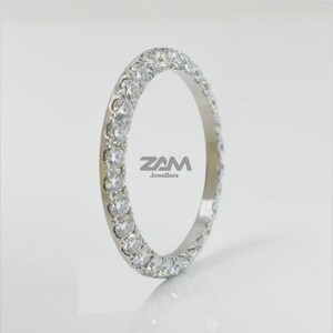 May include: A silver ring with a continuous row of round, clear gemstones. The ring is set against a white background, with the text "ZAM Jewellers" visible on the ring.