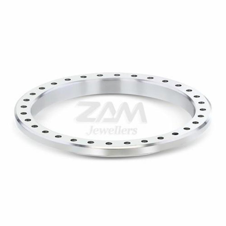May include: A silver-colored ring with a circular design. The ring has a series of small, evenly spaced holes around the outer edge. The text "ZAM Jewellers" is visible in the center of the ring.