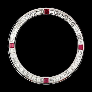 May include: A silver-toned watch bezel with a circular design. The bezel is encrusted with square-cut clear gemstones and features four square red gemstones evenly spaced around the circle. The background is black.