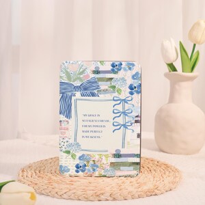 Peut inclure: Plaque rectangulaire décorative avec un motif floral et des nœuds bleus et blancs. La plaque porte l'inscription "MY GRACE IS SUFFICIENT FOR YOU, FOR MY POWER IS MADE PERFECT IN WEAKNESS."