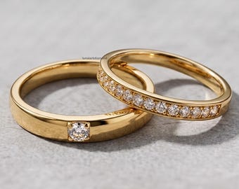Könnte beinhalten: Zwei Goldringe, einer mit einem einzelnen runden Brillantschliff-Diamanten in der Mitte eines glatten Bandes und der andere ein schmales Band, das mit einer Reihe kleiner runder Diamanten besetzt ist. Der Text lunalarkdiamond ist sichtbar.