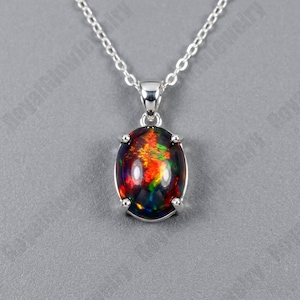 May include: A silver necklace with an oval pendant showcasing a colourful opal gemstone. The opal has red, orange, yellow, and green tones, set in a silver bezel. The chain is a delicate silver link.