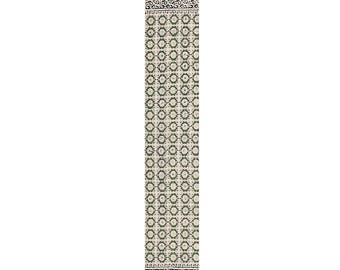 May include: A long, rectangular, off-white runner rug with a repeating green floral pattern. The rug has a black and white patterned border at each end, and a fringe at the top and bottom. This decorative rug is suitable for a hallway or entryway.