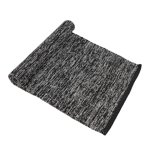 May include: A rectangular rug featuring a textured weave of black and white fibers. The rug is partially rolled at one end, revealing a consistent pattern of interwoven dark and light threads across the entire surface, finished with a solid black edge.