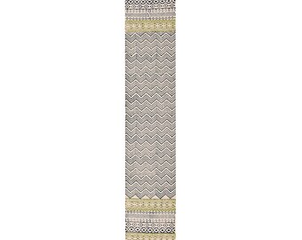 May include: A rectangular, cream-colored runner rug with a repeating black chevron pattern. The top and bottom borders feature geometric designs in black, olive green, and cream, with fringed edges. This rug is suitable for hallways or entryways.