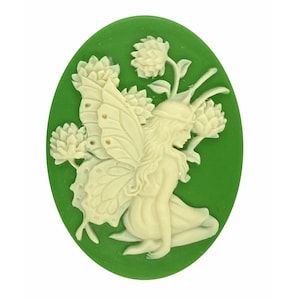 May include: Oval cameo pendant featuring a cream-colored fairy with butterfly wings and flowers, set against a green background. The fairy is kneeling, with detailed floral and wing elements.