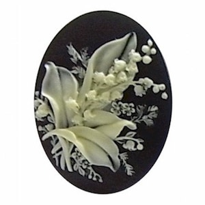 May include: A white cameo with a detailed carving of a bouquet of lily of the valley flowers on a black background.