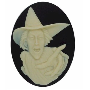 May include: A white cameo featuring a woman wearing a pointed hat and a dress. The cameo is set against a black background.