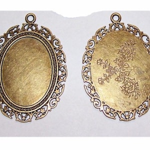 May include: Two antique gold oval-shaped metal frames with intricate filigree designs. One frame is blank, the other has a floral design.