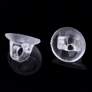 May include: Two clear plastic earring backs. The backs are designed to fit over the post of an earring and have a small hole in the center to allow the post to pass through.