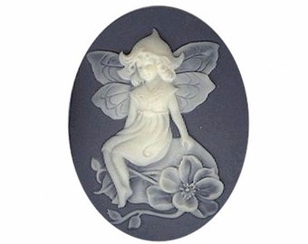 May include: A white cameo featuring a fairy with wings sitting on a flower. The cameo is set in a blue oval background.