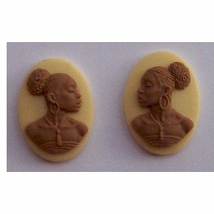 May include: Two brown cameo pendants with a profile of a woman with a bun in her hair. The pendants are oval shaped and have a white background.