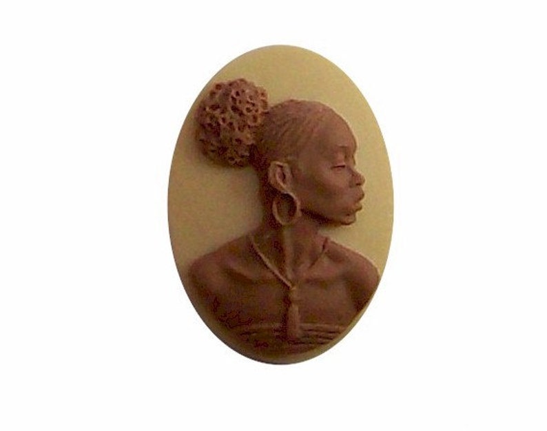 Pu&ograve; includere: Un cammeo marrone che raffigura una donna con un chignon marrone, che indossa una collana e orecchini. Il cammeo &egrave; incastonato in una cornice ovale color crema.