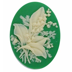 May include: A green oval cameo with a white relief design of lily of the valley flowers.