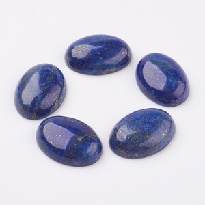 Pode incluir: Cinco pedras preciosas ovais de l&aacute;pis-laz&uacute;li. As pedras s&atilde;o de cor azul profundo com manchas douradas. As pedras est&atilde;o dispostas em um padr&atilde;o circular sobre um fundo branco. Ideais para a cria&ccedil;&atilde;o de joias.