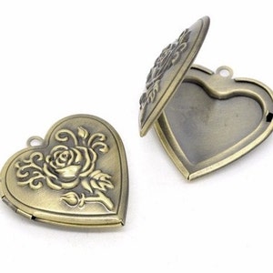 May include: Two heart-shaped lockets made of antique brass-toned metal. One locket is closed, displaying a raised relief design of a rose with swirling stems. The second locket is open, revealing a hollow interior and a small metal loop at the top.