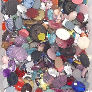 以下が含まれることがあります： さまざまな形、サイズ、色のボタンのコレクション。ボタンには、ファセット宝石、丸型、楕円形、花柄のデザインが含まれます。色はピンク、紫、青、赤から黒、白、黄色まであります。一部のボタンには複雑なディテールがあります。