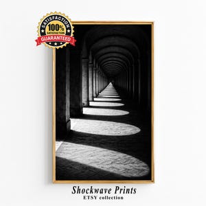 Op de afbeelding: Zwart-wit ingelijste print van een lange gewelfde gang met zuilen, waardoor een perspectief ontstaat. De afbeelding staat in een gouden lijst en bevat de tekst "Shockwave Prints ETSY collection". Een "Satisfaction Guaranteed"-sticker staat in de linkerbovenhoek.