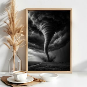 Puede incluir: Una impresión de arte de pared enmarcada que presenta una fotografía en blanco y negro de un gran tornado tocando tierra en un campo bajo nubes oscuras y tormentosas. La impresión está en un marco de madera clara, junto a un jarrón de vidrio.