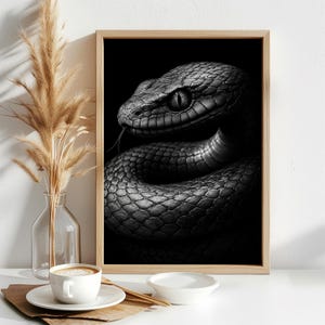 Peut inclure: Une impression d'art mural en noir et blanc encadrée représentant un gros plan détaillé d'un serpent enroulé avec des écailles visibles et une langue fourchue. L'œuvre est présentée dans un cadre en bois clair, mettant en valeur une esthétique monochrome à fort contraste qui souligne la texture de la peau du serpent et ses yeux vifs et concentrés.
