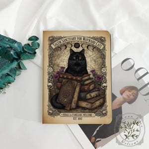 Peut inclure: Un carnet rectangulaire illustré d'un chat noir assis sur une pile de livres. La couverture porte le texte SALEM SANCTUARY FOR WAYWARD CATS, FERALS & FAMILIARS WELCOME et EST. 1692, entouré d'une bordure décorative avec des crânes et des fleurs.