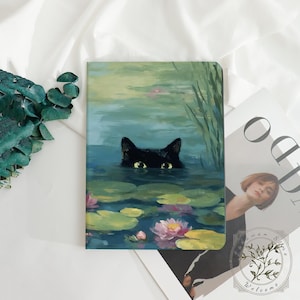 Puede incluir: Un cuaderno con una pintura de un gato negro en el agua, rodeado de nenúfares y flores. Los ojos del gato son visibles sobre el agua. La obra de arte tiene un estilo suave e impresionista con tonos verdes, azules y rosas.