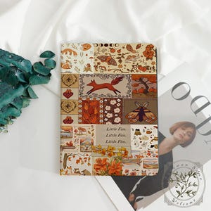 May include: A rectangular notebook featuring a collage of autumn-themed illustrations including foxes, moths, mushrooms, and foliage in shades of orange, brown, and cream. The center contains the text Little Fox. Little Fox. Little Fox. printed in black.