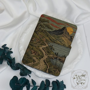 Può includere: Una custodia rettangolare per e-reader con un'illustrazione dettagliata di un paesaggio con colline, piccole abitazioni con porte rotonde, un sentiero in pietra, un lago e una grande montagna sotto una luna gialla e nuvole rossastre.